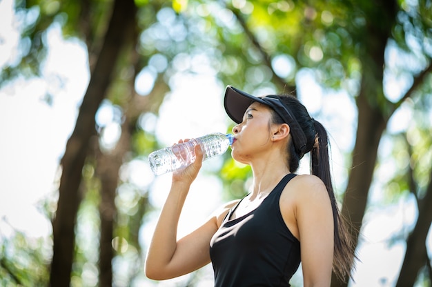 di mezza età Bella donna asiatica di sport che beve acqua dopo il jogging, la salute e il concetto di sport.