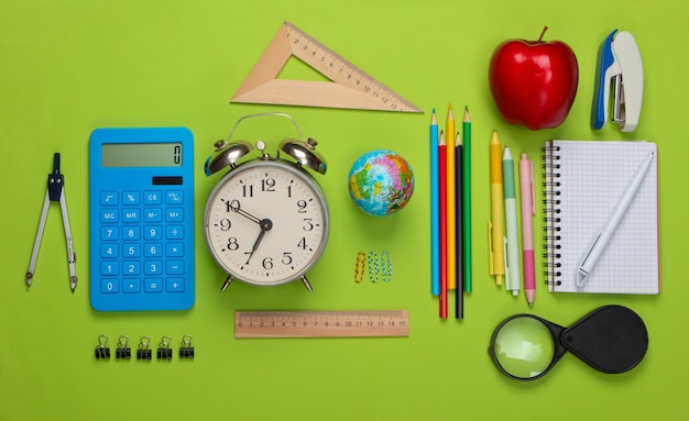 Di nuovo a scuola. Forniture per ufficio e scuola su verde. Educativo, concetto di studio