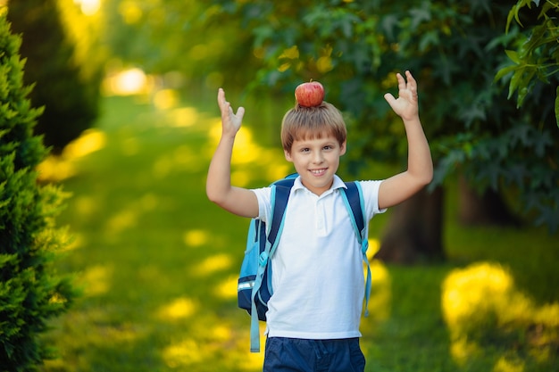 Di nuovo a scuola. ritratto del ragazzo bambino sorridente felice con la mela sulla testa nel parco