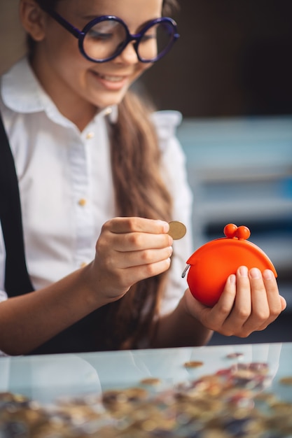 Di risparmio. Ragazza in occhiali che conta i suoi risparmi e che sembra contenta