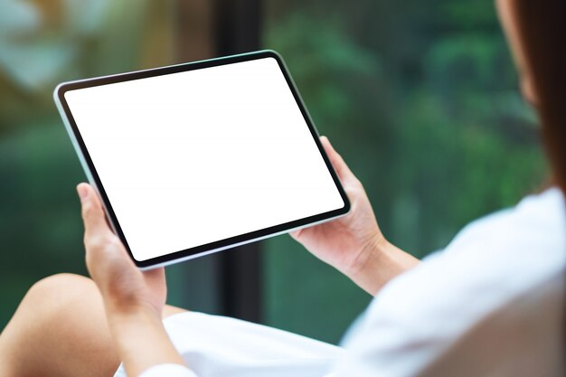 di una donna che tiene il tablet pc nero con schermo desktop bianco bianco, natura verde