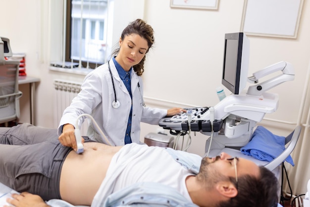 Diagnosi ecografica dello stomaco sulla cavità addominale di un uomo nella vista del primo piano della clinica Il medico esegue un sensore a ultrasuoni sull'addome maschile del paziente Diagnostica degli organi interni