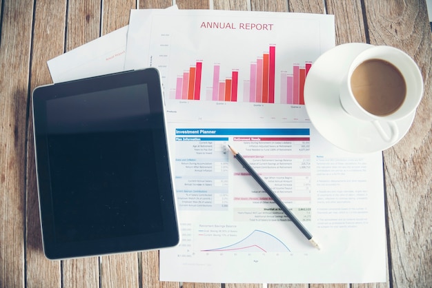 Diagramma e grafico del documento finanziario aziendale del computer portatile dell'ufficio sulla tavola di legno con la tazza di caffè