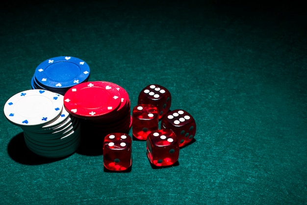 Dices rossi e pila di fiches del casinò sulla tabella verde della mazza