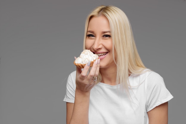 Dieta. Concetto di dieta. Cibo salutare. La giovane donna bionda in maglietta bianca come le mani si ferma su una torta deliziosa. Isolato su sfondo bianco