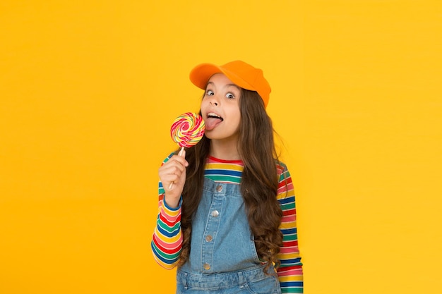 Dieta dello zucchero Caramelle dolci Il mio stile è colorato Tutti i colori dell'arcobaleno Vita luminosa Infanzia felice Bambino elegante e moderno bambino che lecca caramelle lecca-lecca Concetto di dolci e dessert Bambino felice con caramelle