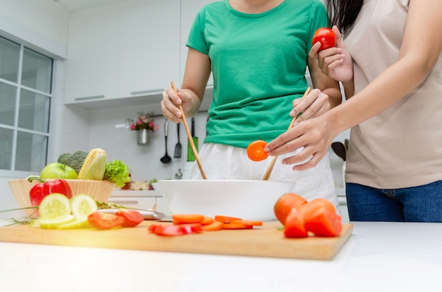 Dieta. due giovane donna graziosa in camicia verde in piedi e preparare l&#39;insalata di verdure