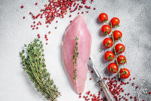 Dieta proteica sana con bistecche di filetto di petto di tacchino crudo ed erbe aromatiche Sfondo bianco Vista dall'alto