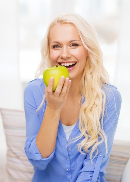 dieta, salute e concetto di casa - donna sorridente con mela verde a casa