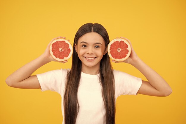 Dieta sana e bellezza della pelle del capretto Ragazza teenager sorridente con la vitamina del pompelmo e la dieta