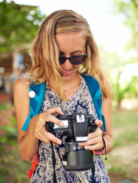 È difficile scegliere la migliore Inquadratura di una giovane donna felice che guarda le fotografie sulla sua fotocamera mentre è in vacanza