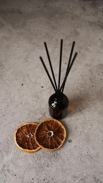 Diffusore a lamella di agrumi su sfondo scuro Bastoncini di bottiglia e arance secche