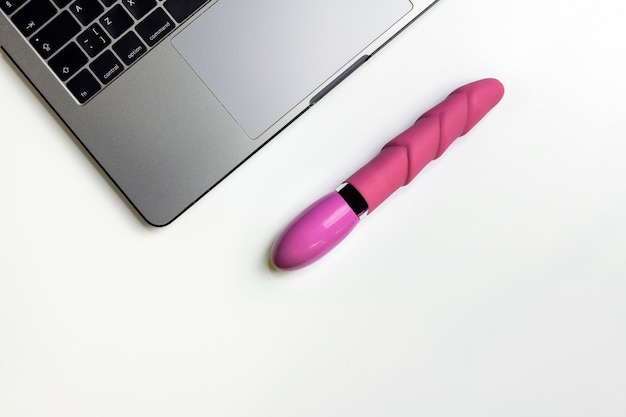 Dildo e laptop sulla scrivania bianca con spazio di copia.