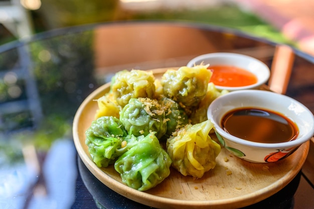 Dim sum di gnocchi gialli e verdi ripieni di carne di maiale e gamberi con salse