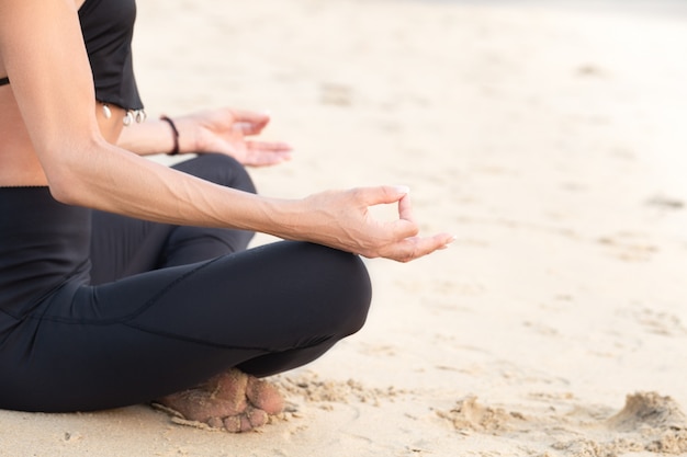 Dimagrisca la donna matura nello yoga di pratica nero sulla spiaggia di sabbia