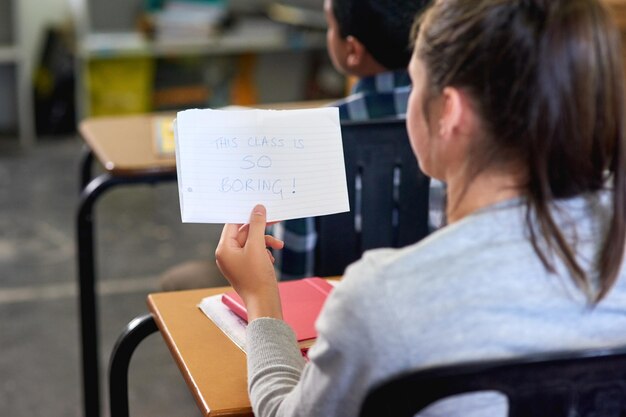 Dimmi qualcosa che non so Inquadratura posteriore di una scolaretta non identificabile che legge un appunto in classe