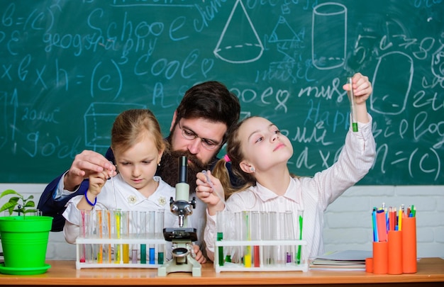 Dimostralo Bambine che eseguono esperimenti sotto la supervisione dell'insegnante Bambini di piccole scuole che tengono provette per esperimenti di laboratorio Dimostrazione ed esperimento