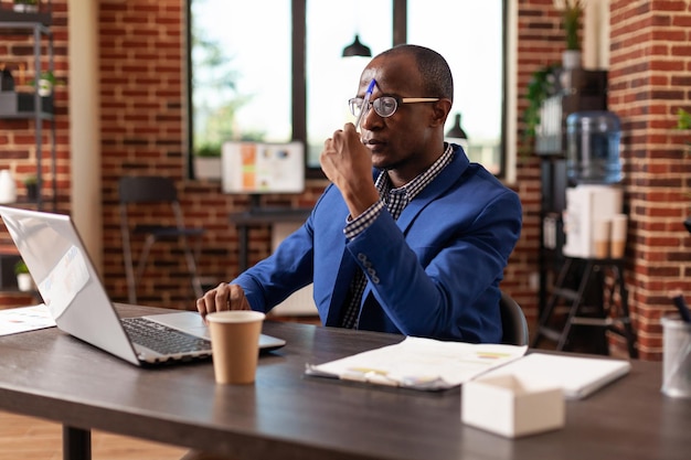 Dipendente che pensa al progetto aziendale e alla soluzione di brainstorming sul laptop. Imprenditore pensieroso che ha pensieri sulle idee finanziarie mentre usa il computer nell'ufficio dell'azienda.