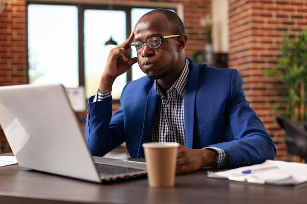 Dipendente che pensa alla pianificazione del progetto e utilizza il laptop per trovare la strategia aziendale. Persona pensierosa che utilizza computer e idee di brainstorming per pianificare il successo e la gestione dell'azienda.