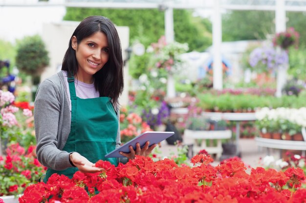 Dipendente che sceglie i fiori con il pc della compressa nel Garden Center