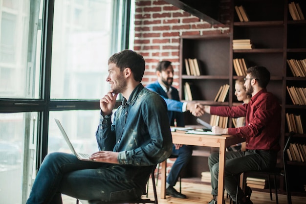 Dipendente dell'azienda con laptop che guarda fuori dalla finestra