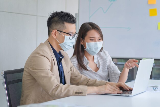 Dipendenti di affari che indossano maschera durante il lavoro