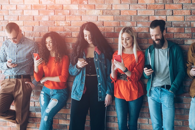 dipendenza dai social. fila le persone con gli smartphone. stile di vita dei millennials. tempo libero tecnologico.