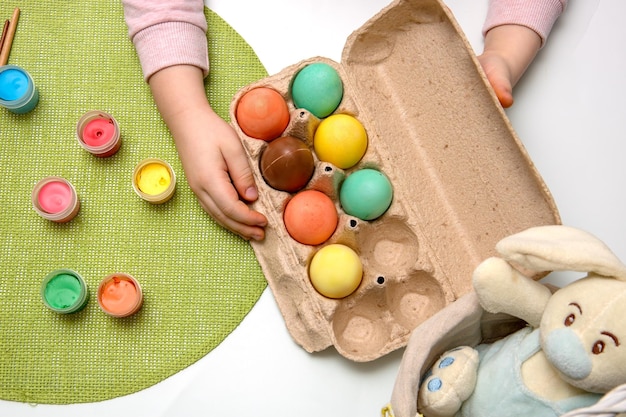 Dipinge un cesto con un coniglietto pasquale un contenitore con uova di Pasqua colorate tenute dalle mani dei bambini