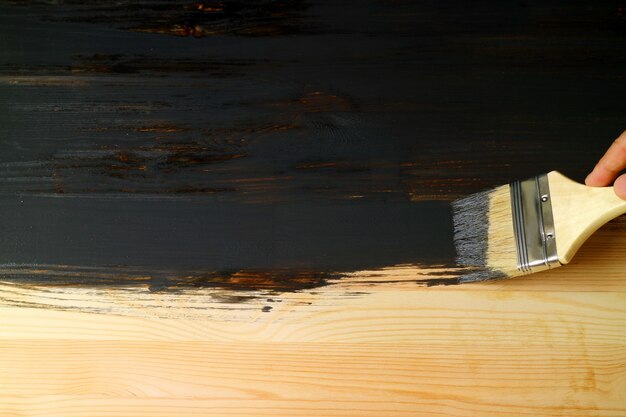 Dipingere a mano la superficie della tavola di legno naturale con il pennello