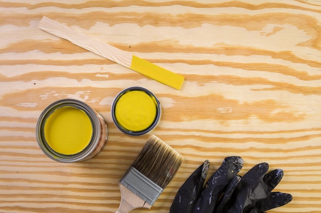 Dipingi in un barattolo di vernice metallica e strumenti per pittori su una tavola di legno.