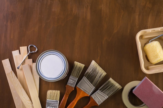 Dipingi in un barattolo di vernice metallica e strumenti per pittori su una tavola di legno.