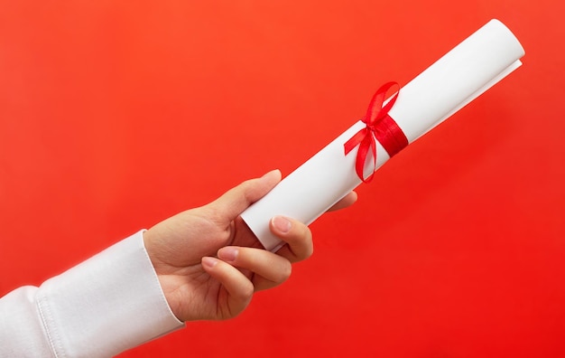 Diploma della stretta della mano della donna con il nastro rosso su fondo rosso