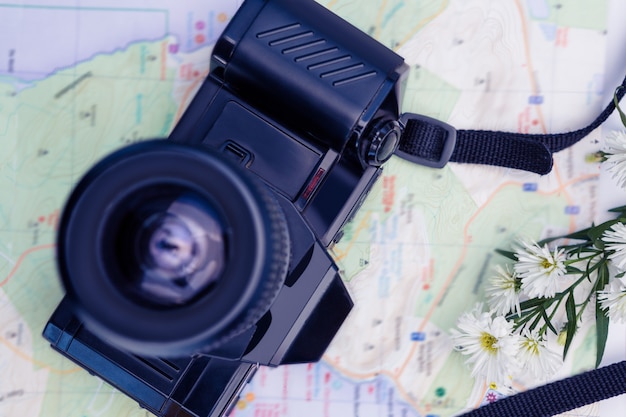 Direttamente sopra colpo di fotocamera digitale e mappa e fiori sul tavolo