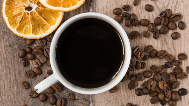 Direttamente sopra il colpo di caffè nero con fagioli e arance sul tavolo