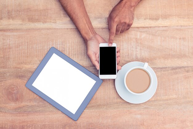 Direttamente sopra il colpo di persona che utilizza smartphone da caffè e tablet sul tavolo