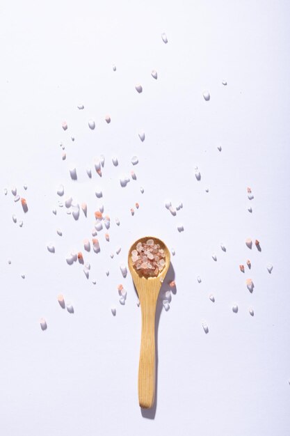 Direttamente sopra il colpo di salgemma rosa su un cucchiaio di legno su sfondo bianco. inalterato, ingrediente, alimento, salgemma e condimento.