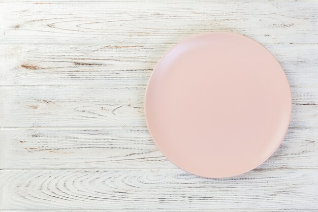 Direttamente sopra il piatto opaco rosa vuoto su fondo di legno bianco con lo spazio della copia