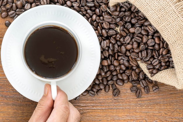 Direttamente sopra la foto della mano con la tazza di caffè e i fagioli sul tavolo