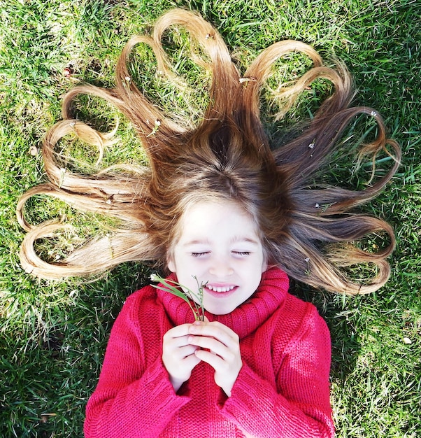 Direttamente sopra la foto di una ragazza sorridente sdraiata sul campo erboso