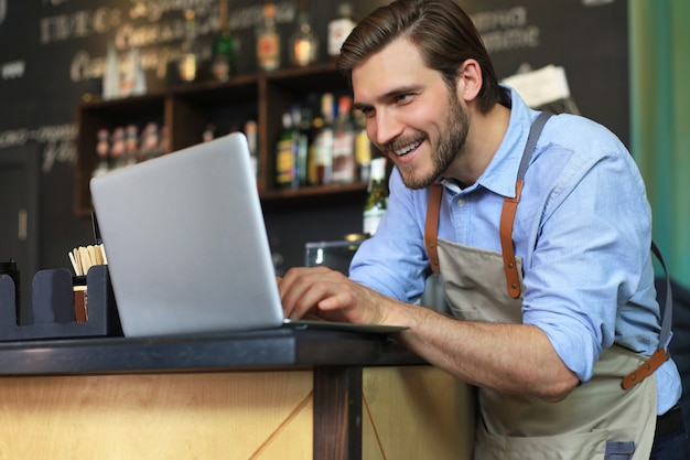 Direttore del ristorante che lavora al computer portatile, contando i profitti.