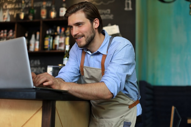 Direttore del ristorante che lavora al computer portatile, contando i profitti.