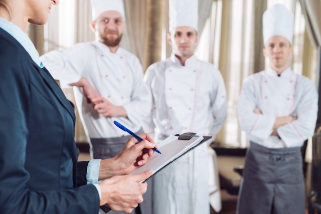 Direttore del ristorante e il suo staff in cucina. interagendo con lo chef in cucina commerciale.