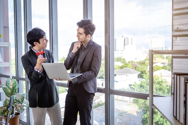 Dirigente dell'azienda Giovane uomo d'affari asiatico e assistente segretario personale di coaching Uomo d'affari omosessuale partner LGBT mentre lavorano insieme a computer portatile e strategia negli affari in ufficio