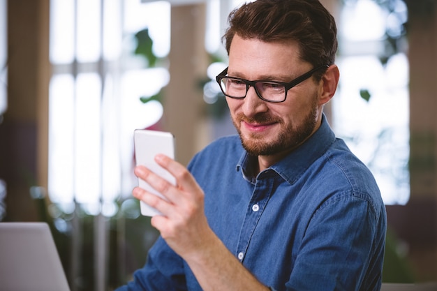 Dirigente felice che per mezzo del telefono cellulare all'ufficio