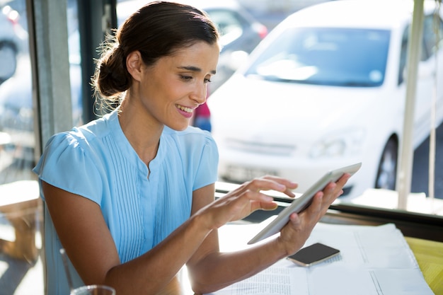 Dirigente femminile utilizzando la tavoletta digitale al caffè