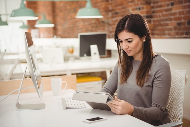 Dirigente femminile utilizzando la tavoletta digitale allo scrittorio