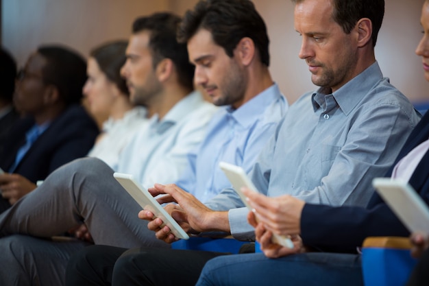 Dirigenti aziendali che partecipano a una riunione di lavoro utilizzando la tavoletta digitale al centro conferenze