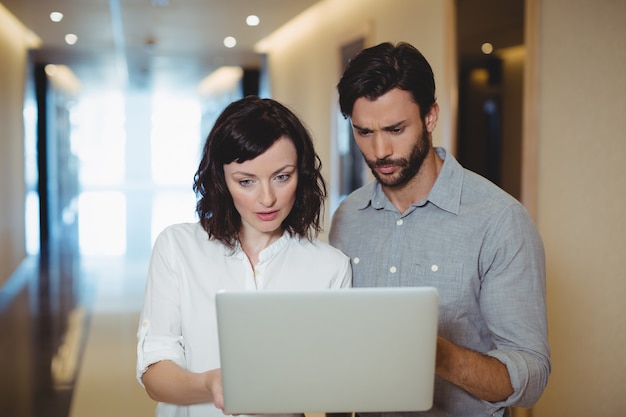 Dirigenti maschii e femminili che utilizzano computer portatile in corridoio