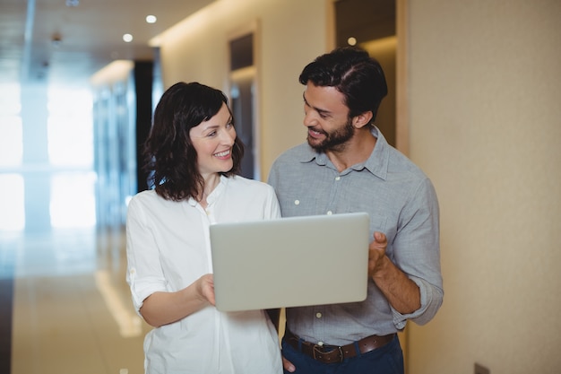 Dirigenti maschii e femminili che utilizzano computer portatile in corridoio