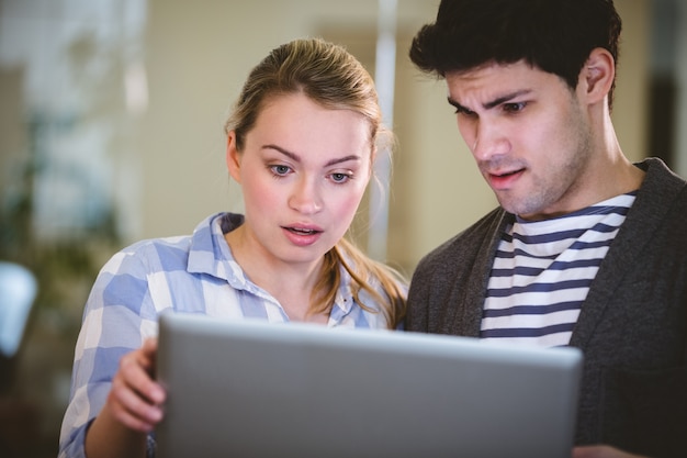 Dirigenti sorpresi che esaminano computer portatile in ufficio creativo